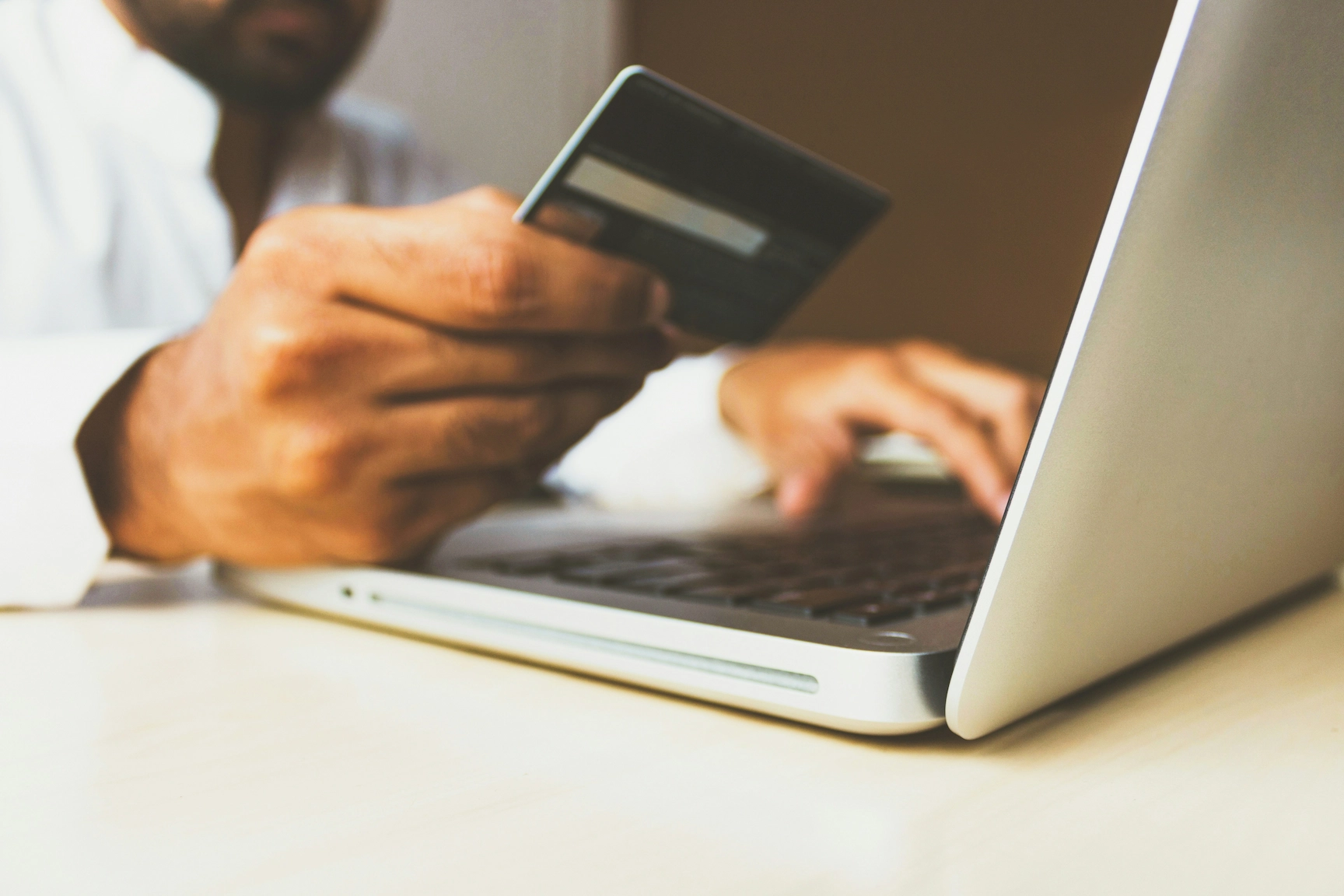 Person online shopping with credit card and laptop.
