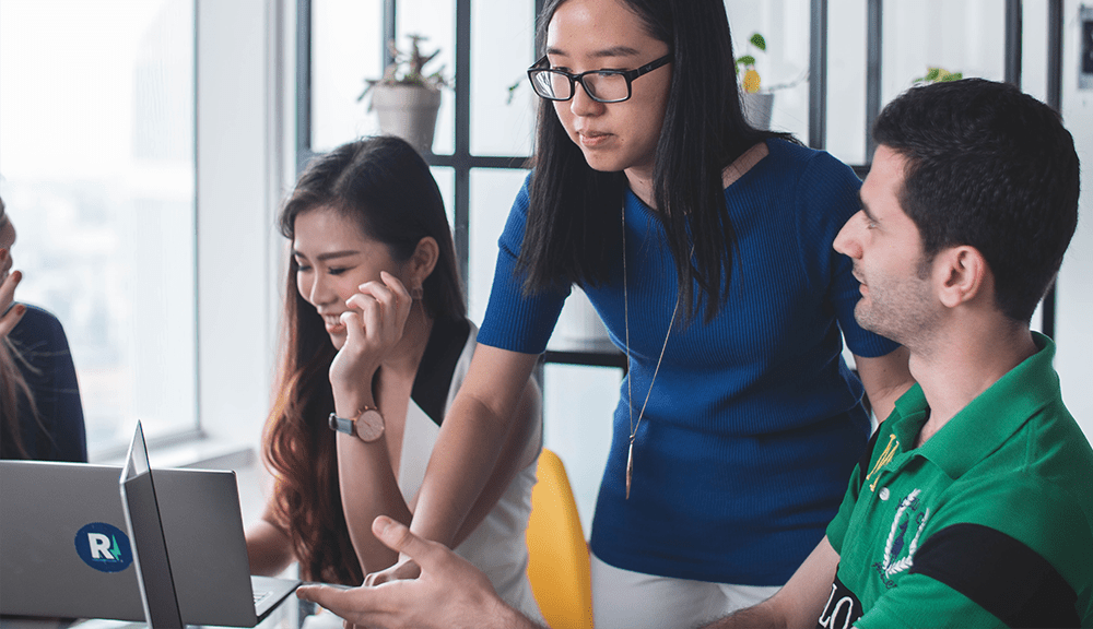 Team collaborating in office with laptops.