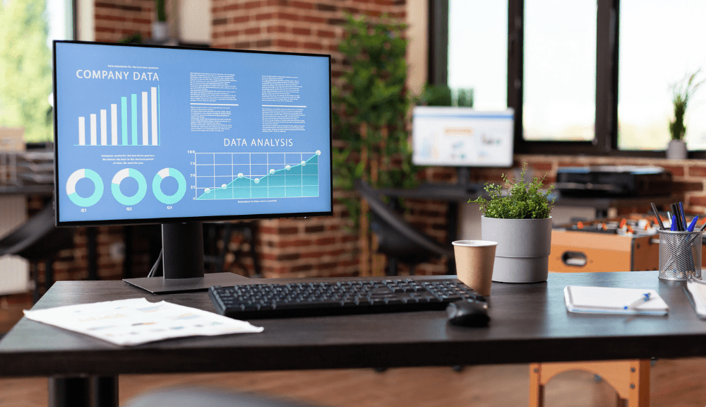 Office desk with computer showing data analysis.