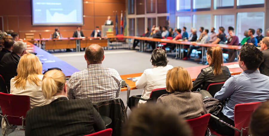 Conference meeting with a large audience seated.
