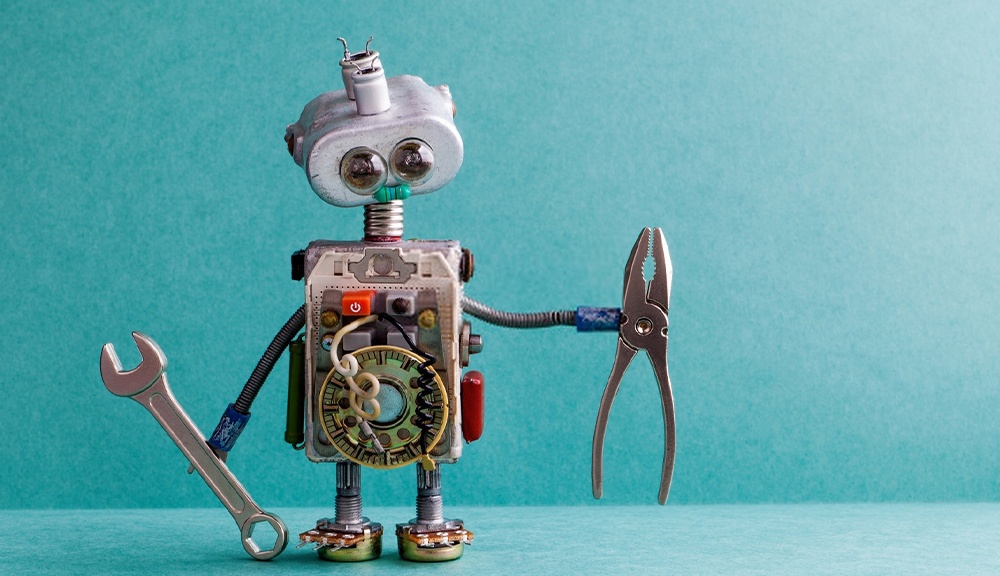 Robot holding wrench and pliers on blue background.