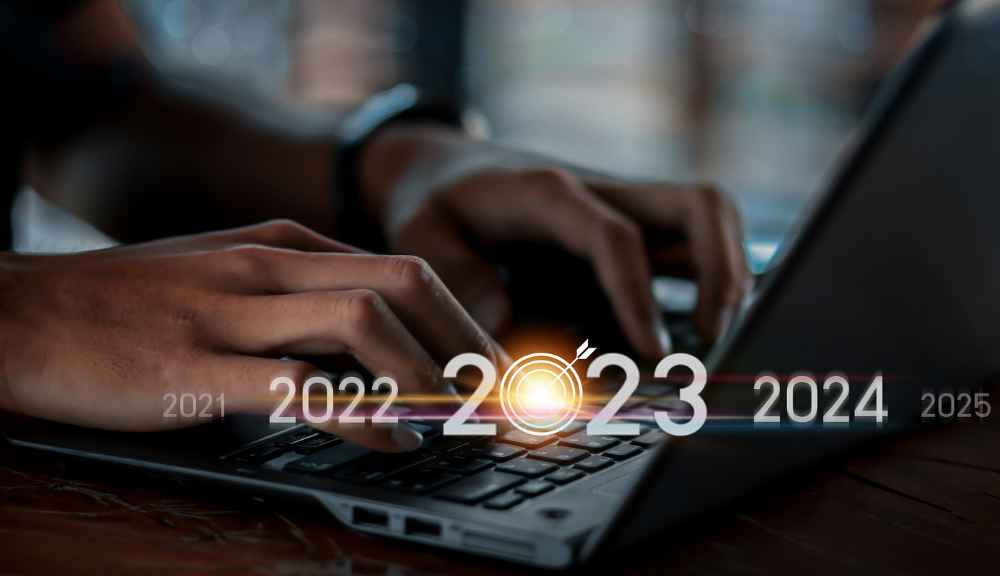 Typing on laptop with 2023 glowing target graphic.