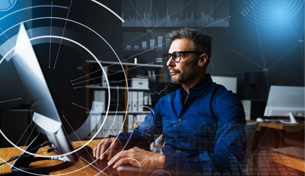 Man working on computer with digital graphics overlay.