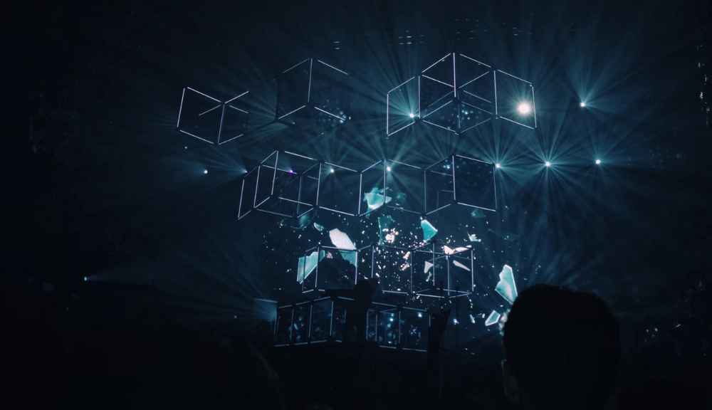 Abstract light show with geometric shapes on stage.