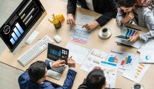 Business meeting with charts and graphs on table.