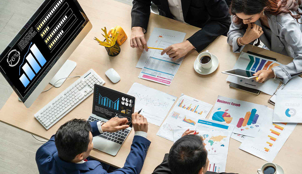 Business meeting with charts and graphs on table.