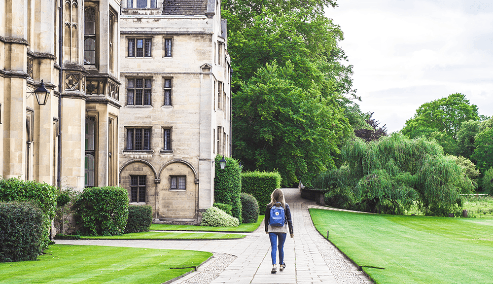 Person walking near historic building and garden