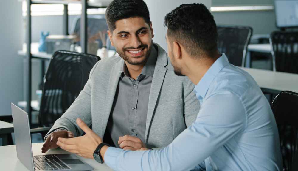 Two men discussing at a laptop in office.