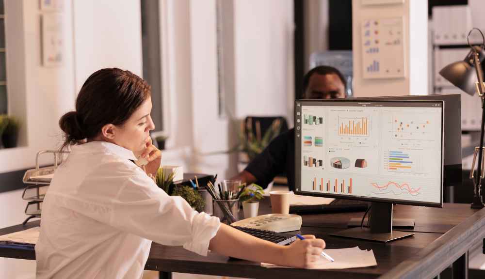 Woman analyzing charts on computer in office.