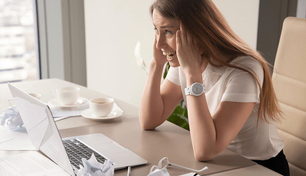 Stressed woman at desk with laptop