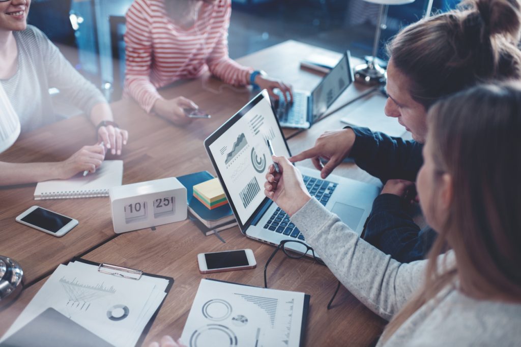 Business team looking at a data report using laptops during meeting