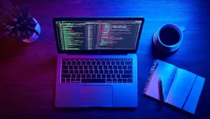 Laptop with code, notebook, and coffee on desk