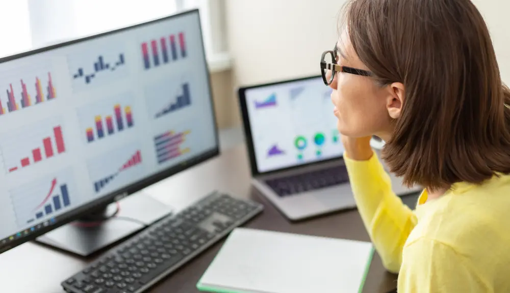 Personne analysant des graphiques sur écran d'ordinateur.