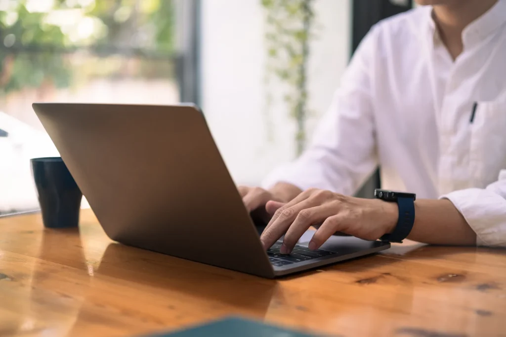 Person typing on laptop at wooden table