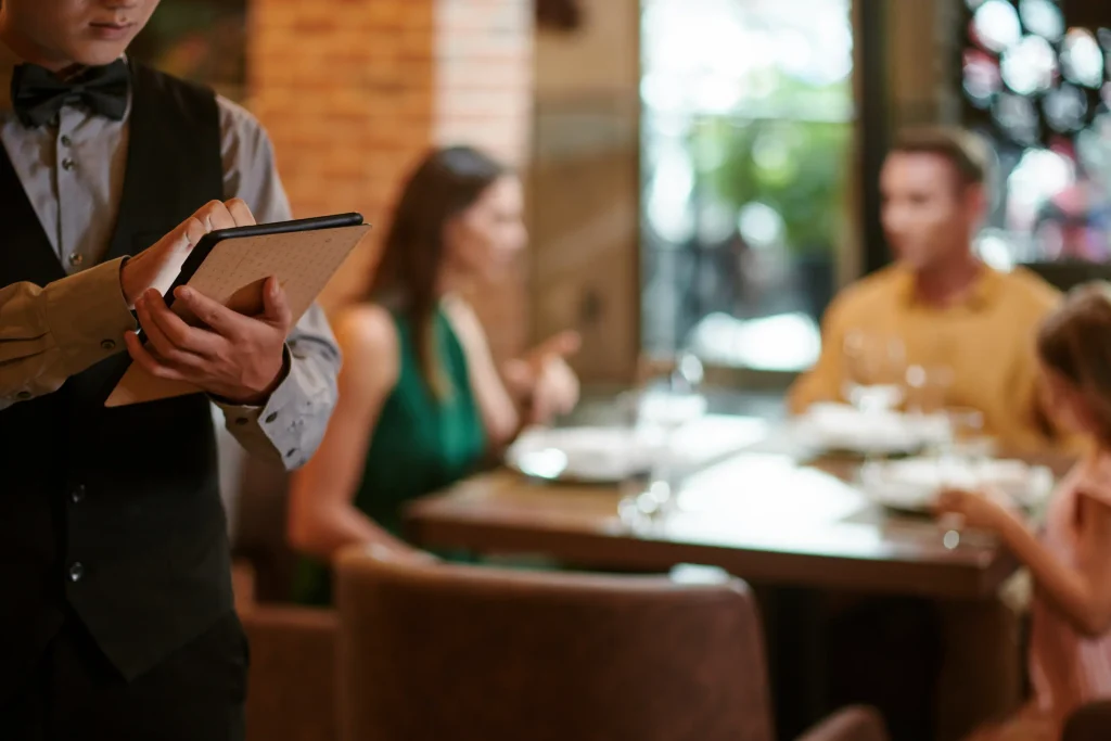 Waiter taking order on tablet at restaurant