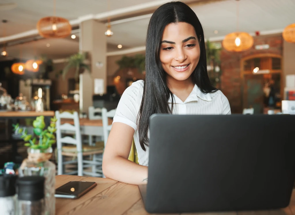 Woman smiling while using laptop in cafe